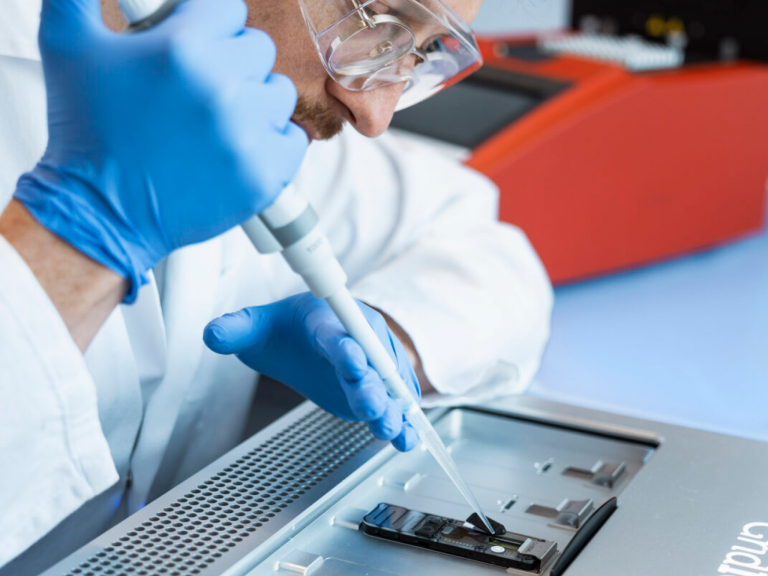 Laborant wie er mit einer Pipette eine Lösung auf eine Testchip bringt