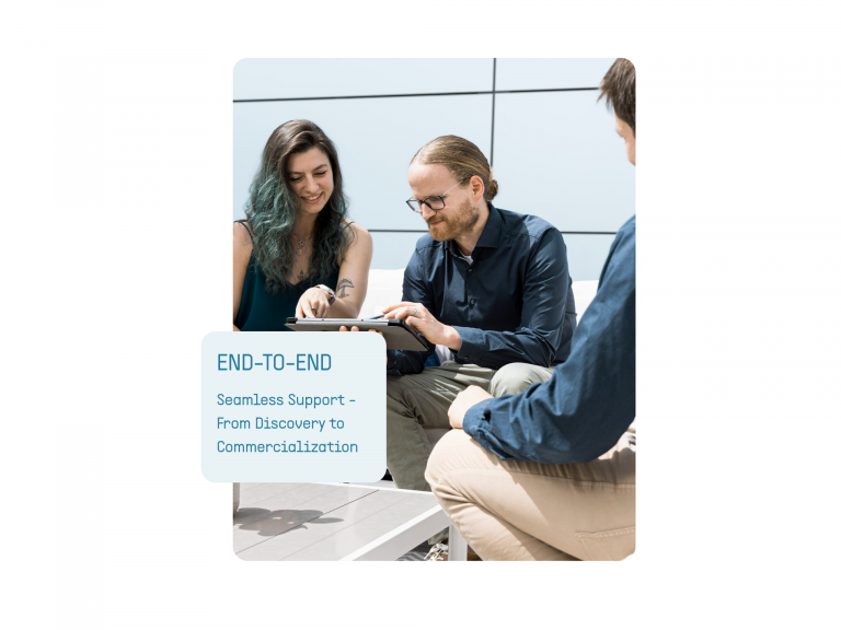 Fotoausschnitt von drei Mitarbeitern zeigend auf einem Tablet, mit einer Karte oben drüber mit dem Text End-to-End Seamless Support From Discovery to Commercialization